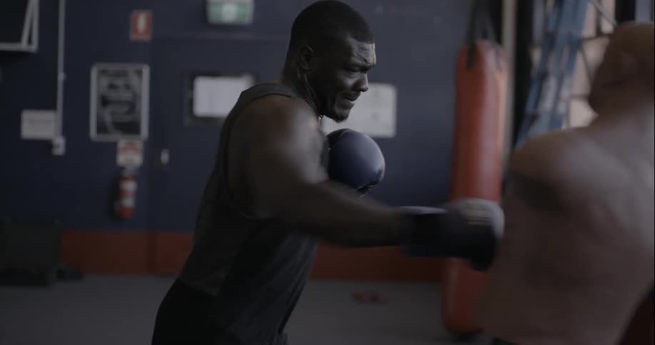 A man is boxing a dummy in a gym