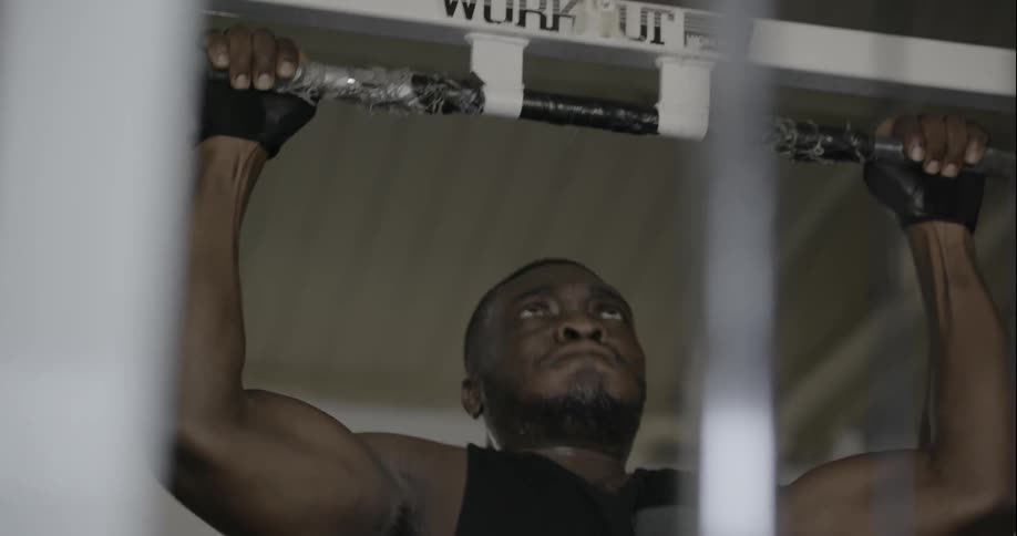 A man is doing pull ups in a gym