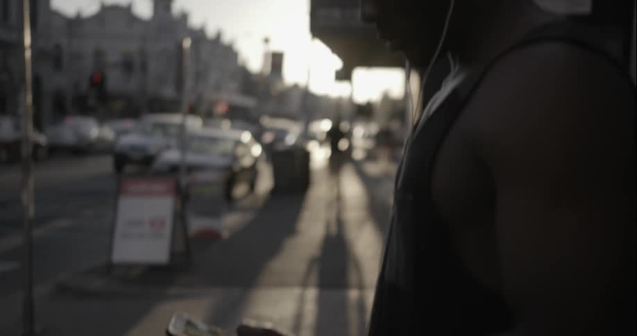 Man using a smartphone on a city street at dusk