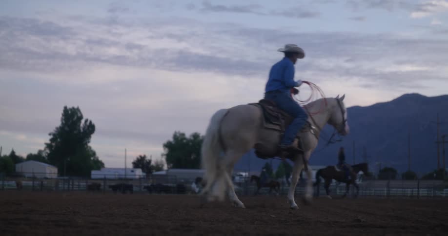A man putting on a blue shirt riding a white horse