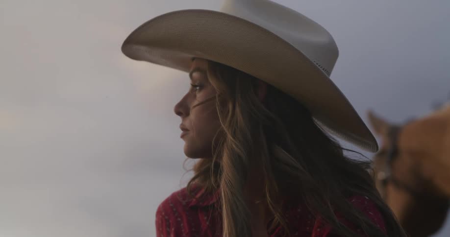 A woman with a cowboy hat and a contemplative look