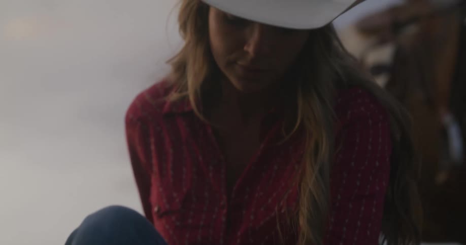 Cowgirl crouching down and picking up some soil in her hands