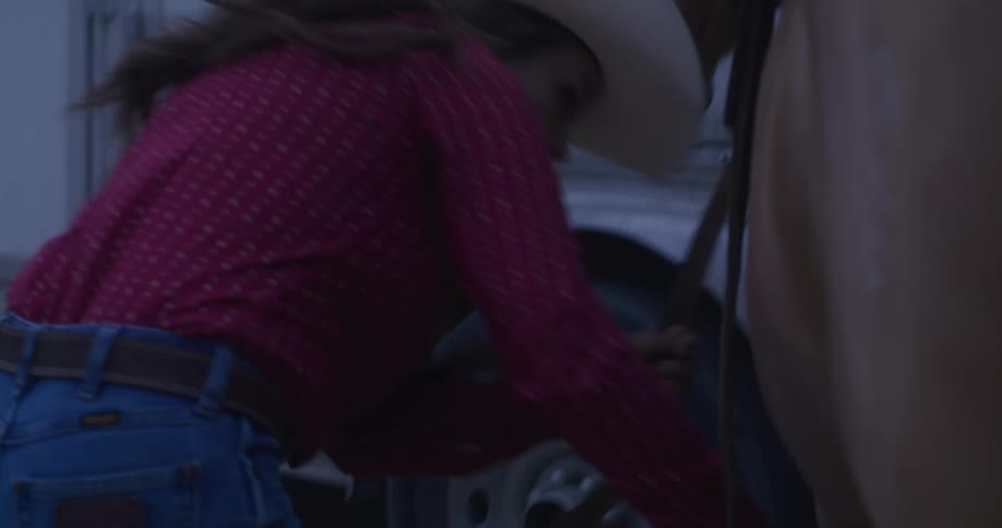 Cowgirl tightening the saddle straps on her horse in the morning