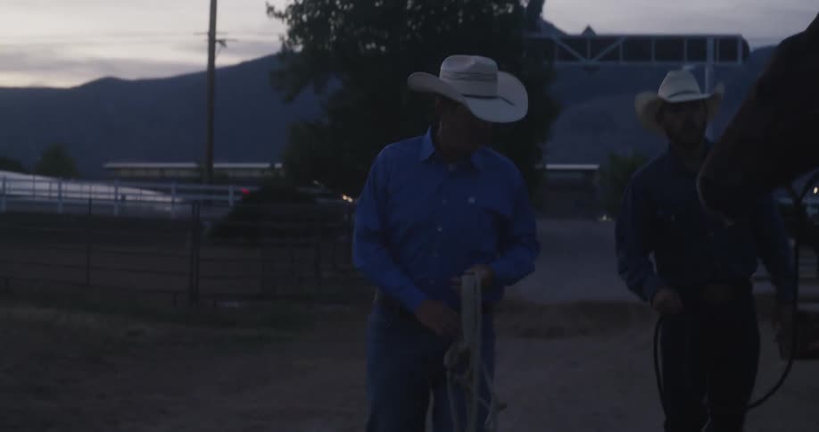 Man handing a cowboy a rope on a ranch