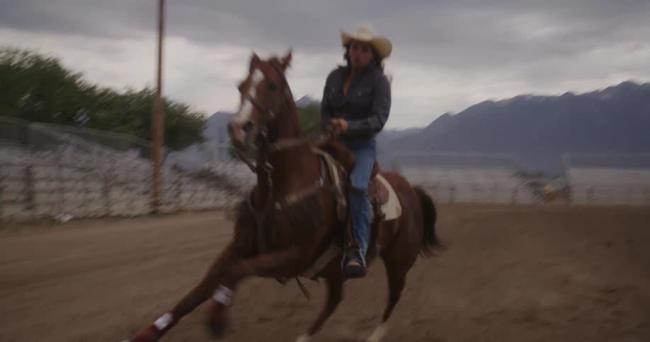 Horse rider rides quickly across ground while practicing in rodeo arena