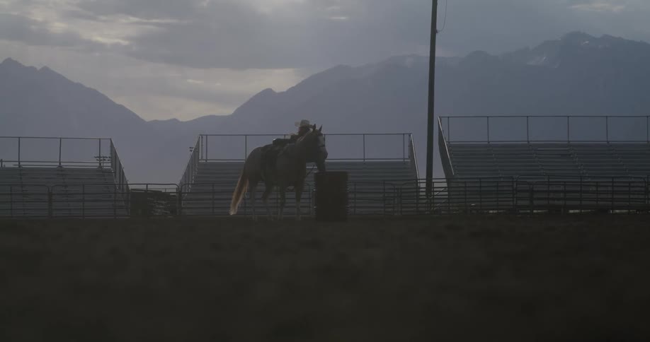 Person dismounting from a horse in the middle of a rodeo arena