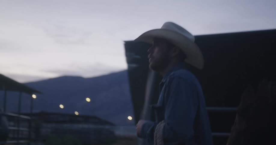 Cowboy leads a horse through the ranch at morning