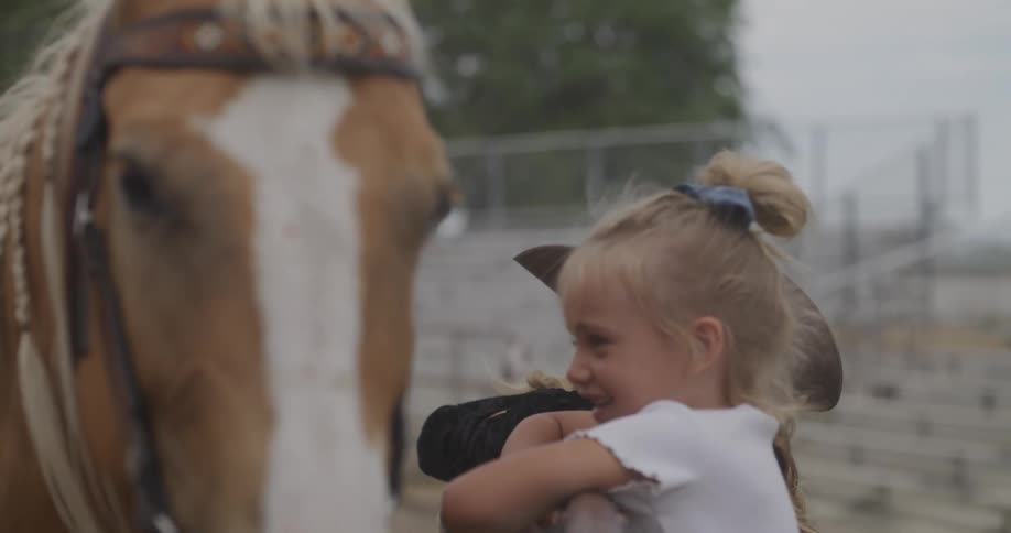 A lady on a horse watching her kids pet the horse