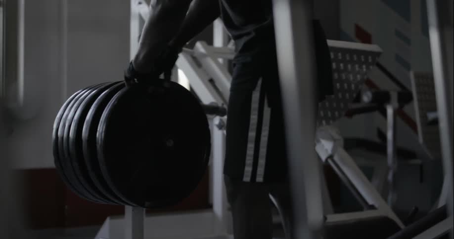 A man picks up a weight plate and walks