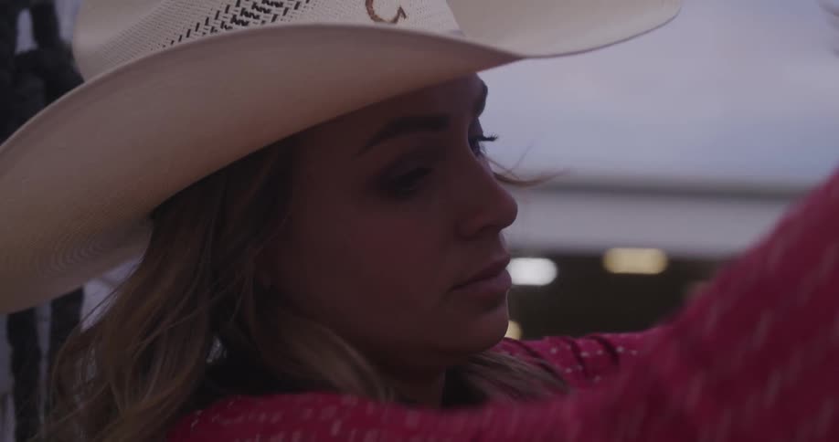 Cowgirl adjusts the reins of a horse a morning