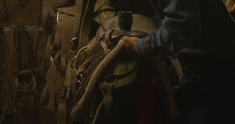Cowboy brings a saddle out of storage