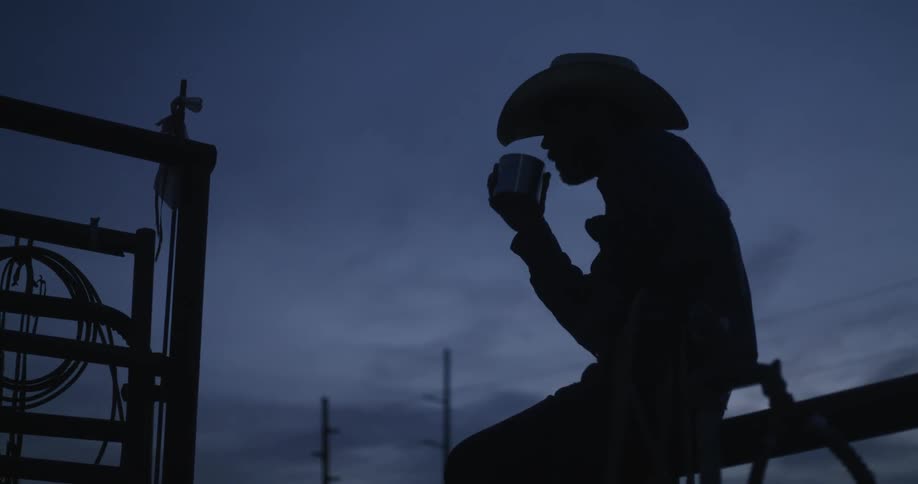 A man resting on a barricade and having a drink