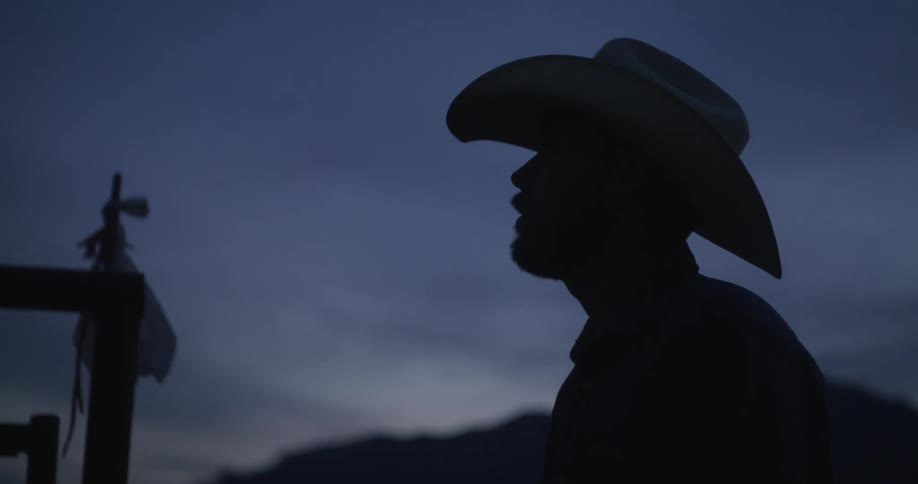 Silhouette of a cowboy drinking coffee at dawn