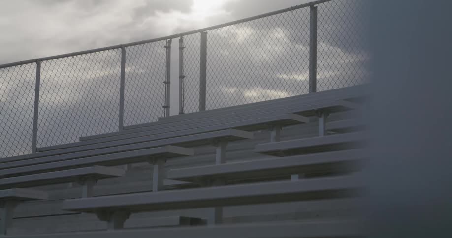 A stadium with series of benches and a fence behind