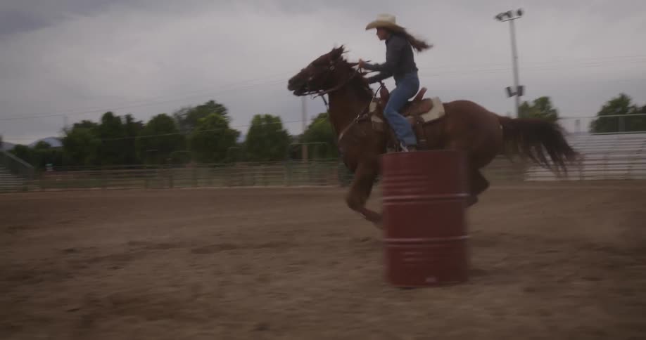 Woman riding a horse at high speed in a rodeo field
