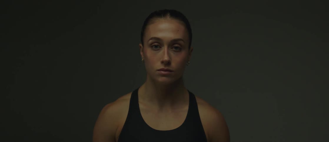 A blueeyed woman standing in front of a gray wall
