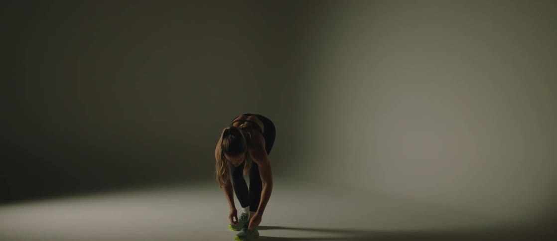 A female indoor knotting her running shoe