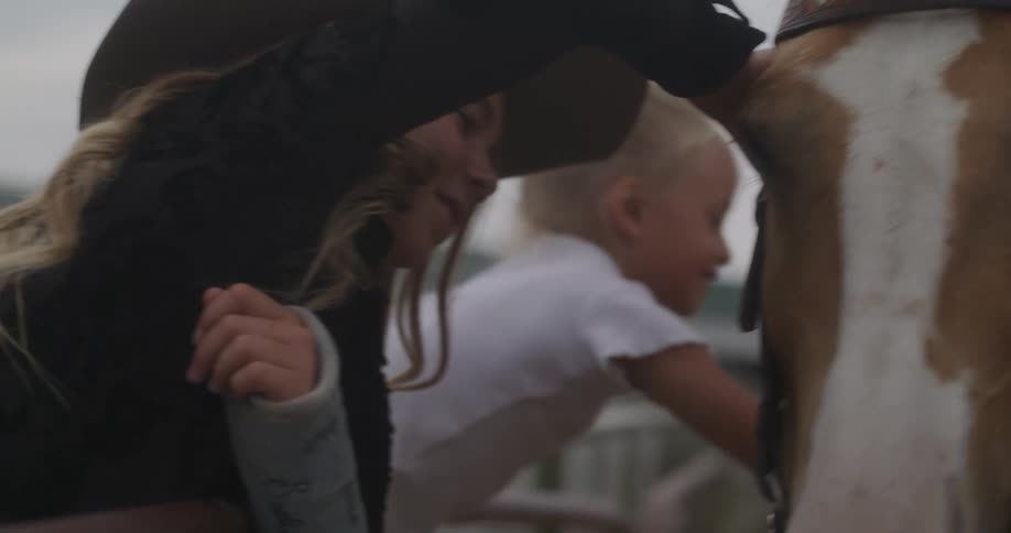 Girls caress a horse in a rodeo