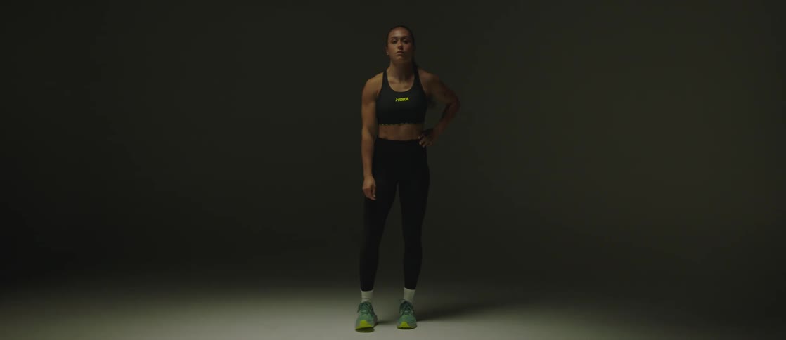 A woman in gym clothes squats and adjusts her tights