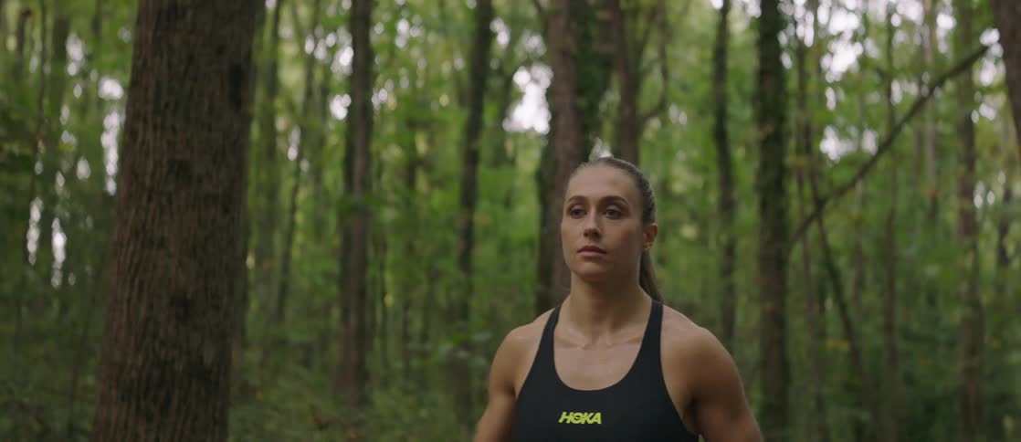 A woman is jogging through the woods