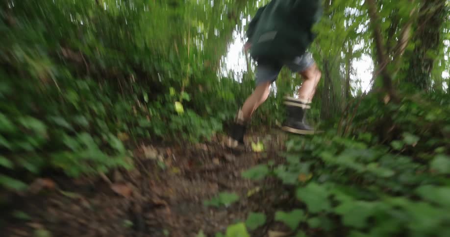 A boy runs on a trail in the forest