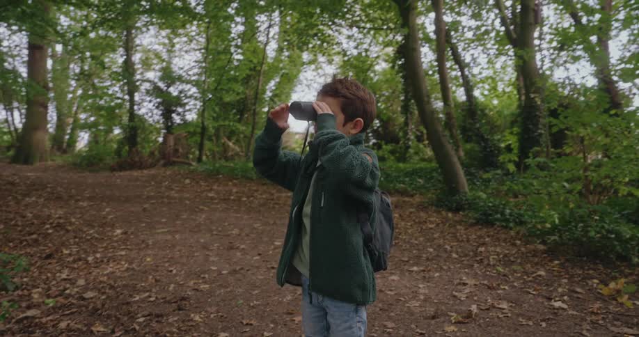 Child with binoculars in the middle of a forest