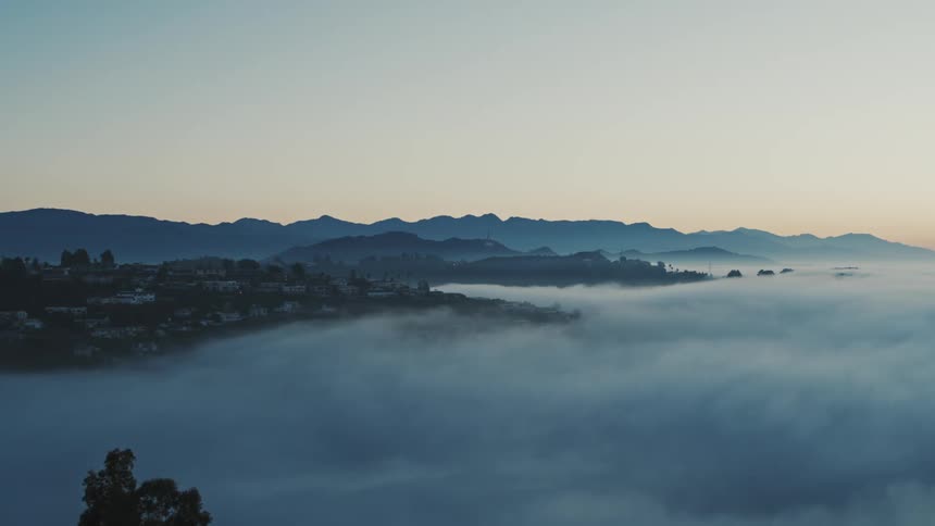 A thick layer of lowhanging clouds moves through the Hollywood Hills before dawn