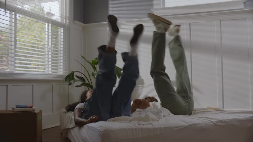 Man and woman holding hands happily throwing themselves on the mattress