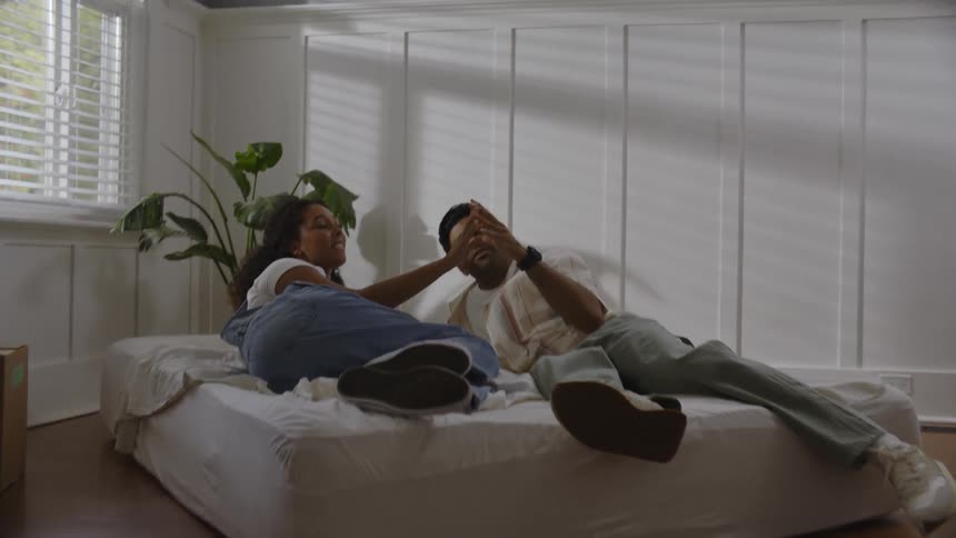 Man and woman lying in bed and holding hands