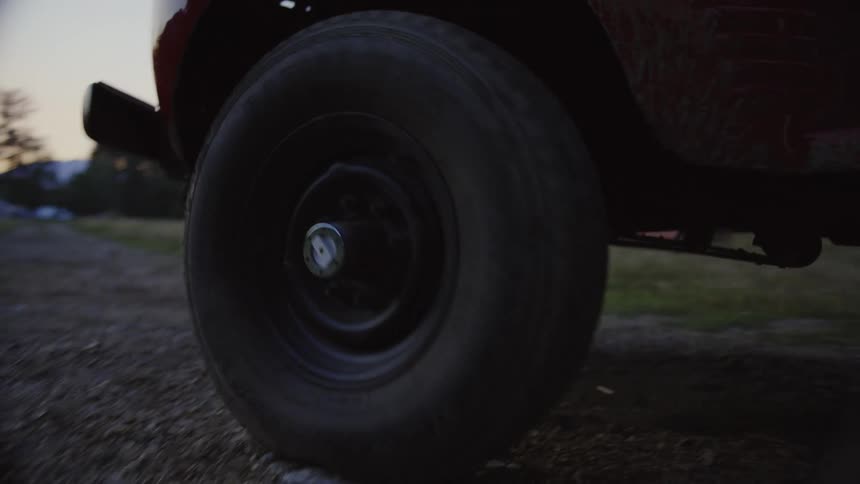 Old red truck moving on a rural road at sunset