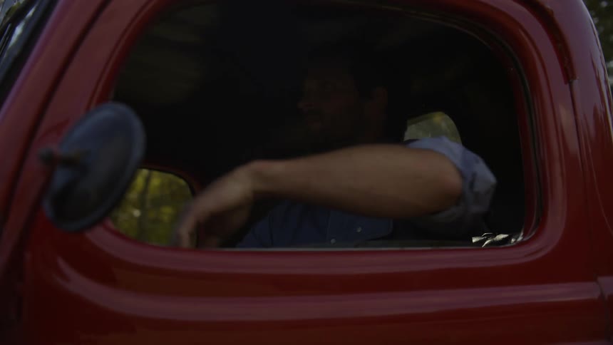 A man driving in a red pickup truck