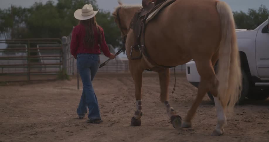 Cowgirl leads a horse through the ranch