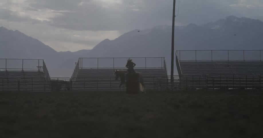 Cowgirl rides a horse next to a red barrel in the rodeo