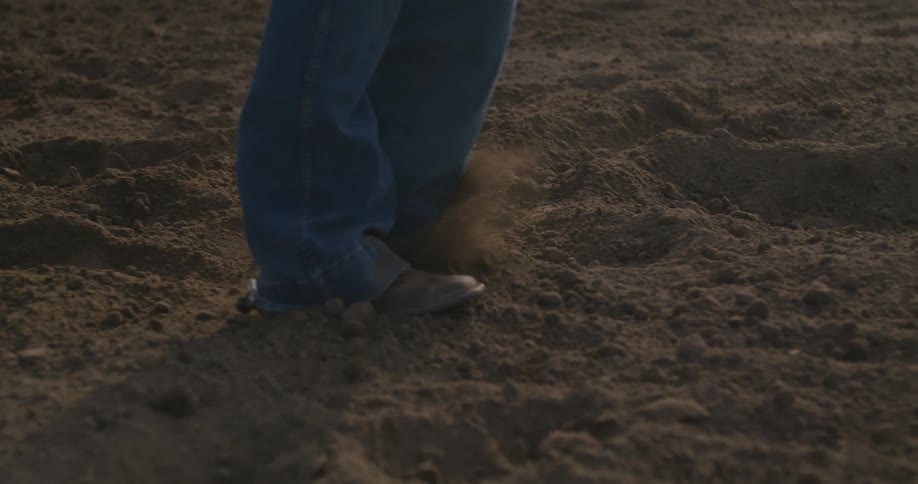 A person with a horse is kicking dirt to close holes on a field