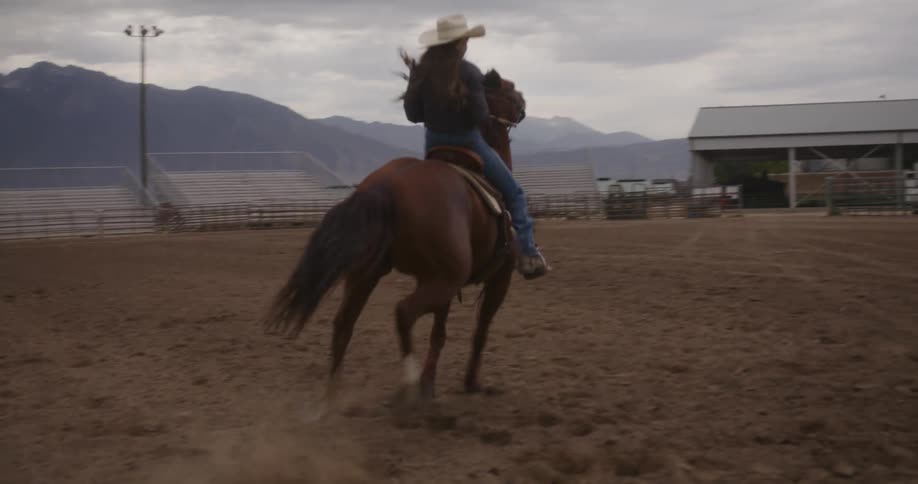 A woman on a horse running through the dirt arena