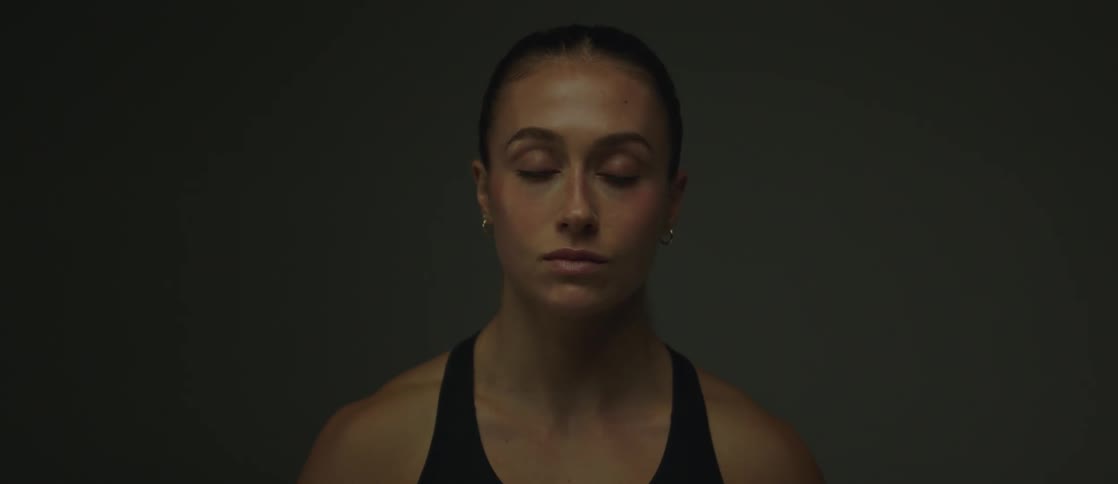The face of a woman wearing a tank top and looking forward while blinking