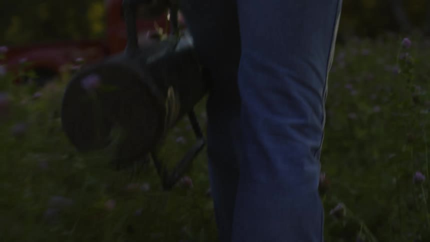 Man carries object across rural yard toward red pickup truck