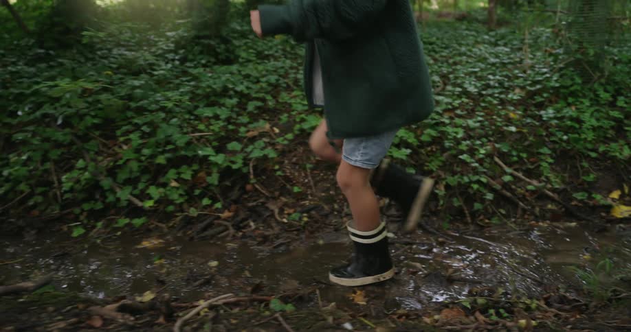 A boy walking through the forest in black boots