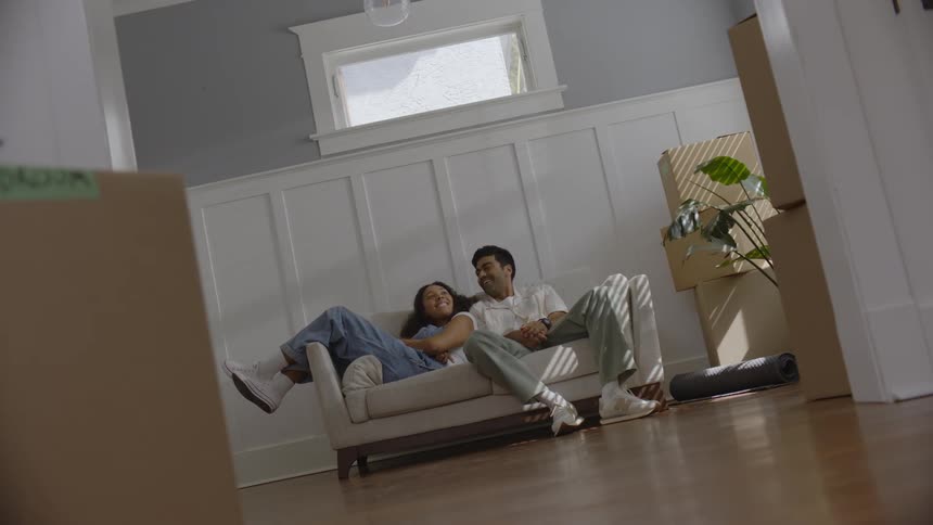 Man and a woman sits on a sofa indoor after moving it