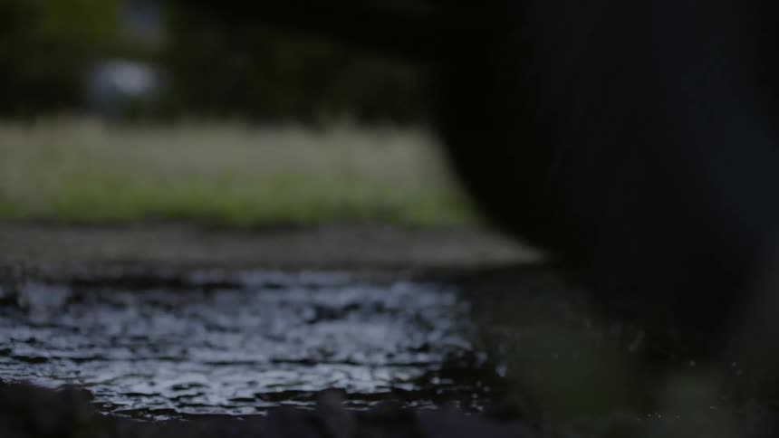 A vehicle drives through a muddy water puddle
