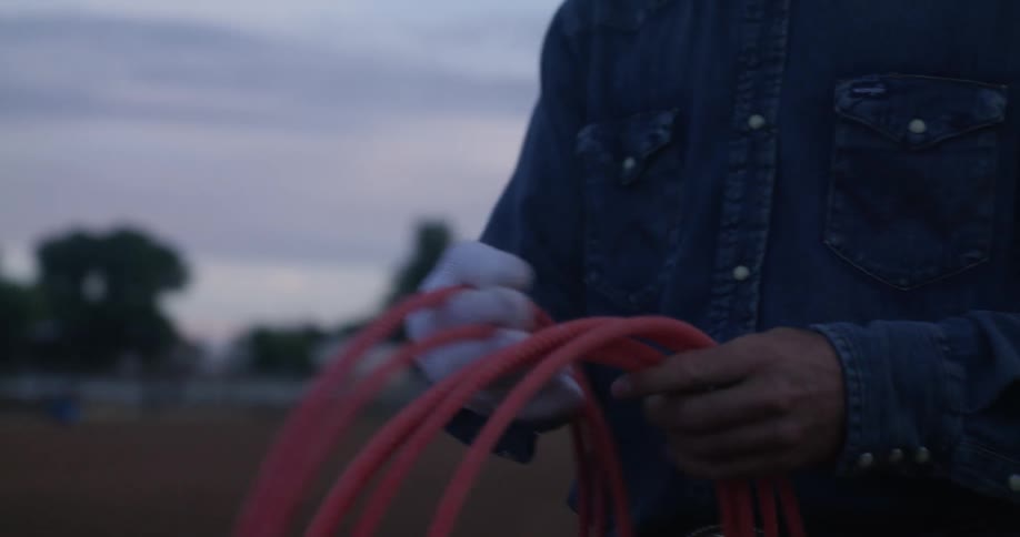 A person winding a rope around his hands at dusk