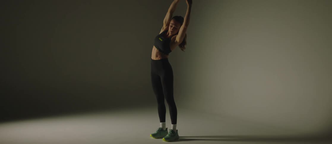 A woman in gym clothes exercising by stretching