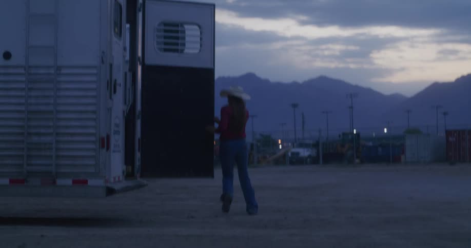 A woman opening the back of a parked trailer