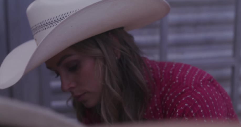 A woman wearing a cowboy hat focused on her task