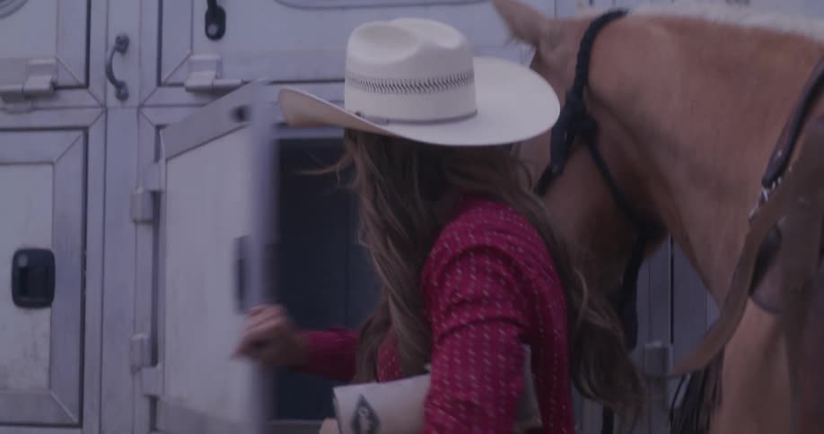 A woman taking something from a vehicle door and there is a horse next to her