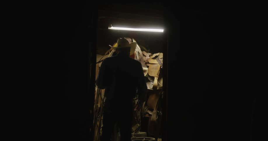 Cowboy walking backward inside an indoor space