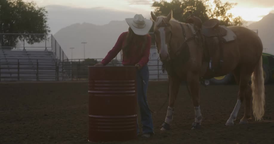 Cowgirl carries a red metal barrel to the rodeo