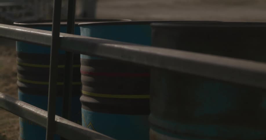 Three barrels sit against metal framework outdoors