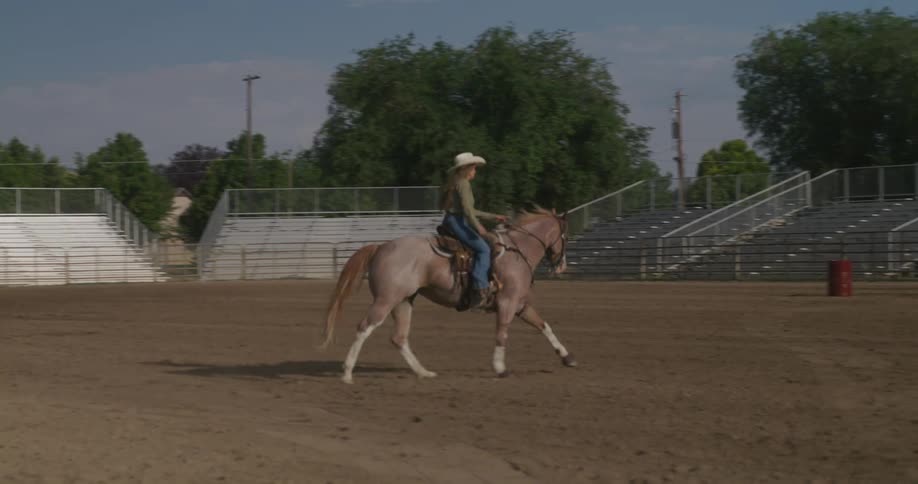 A lady riding a horse on a sandy field during the day