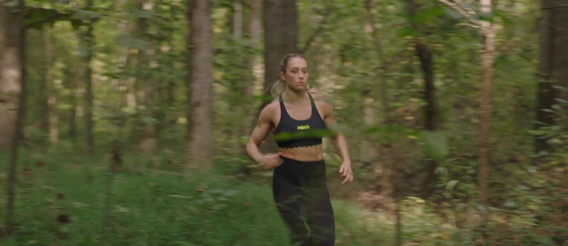 A woman in exercise clothes runs through a forest